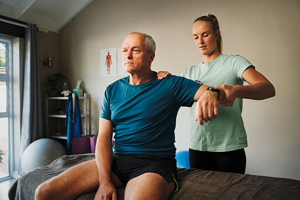 An athletic trainer helps a client stretch an injury in their elbow.