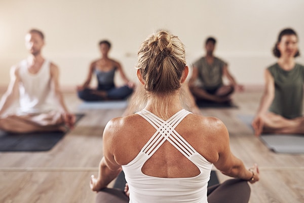 A yoga instructor calmly leads her class knowing she is backed by the best yoga insurance.
