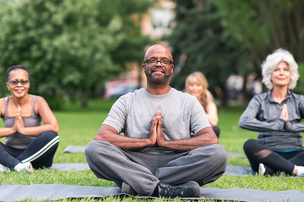 A yoga teacher leads his class in an outdoor session because his yoga insurance allows him to teach outside of a studio.