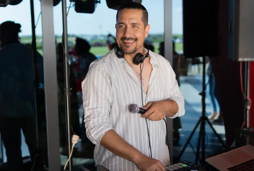 A DJ at his booth at a party holding a mic.