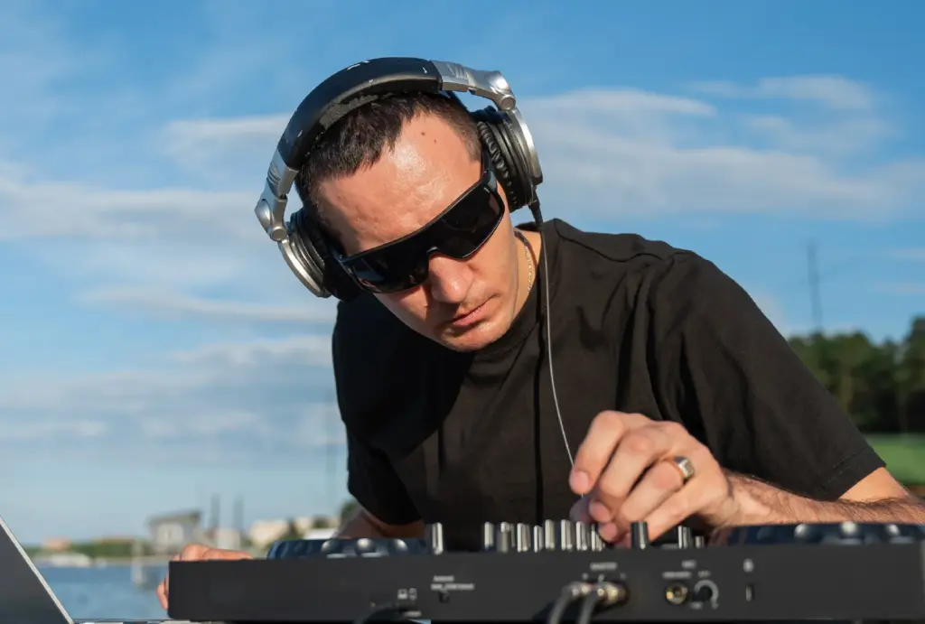 A DJ at the beach adjusting his gear.